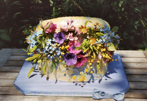 The cake is filled with pincushion flowers roses lilies ivy and berries 